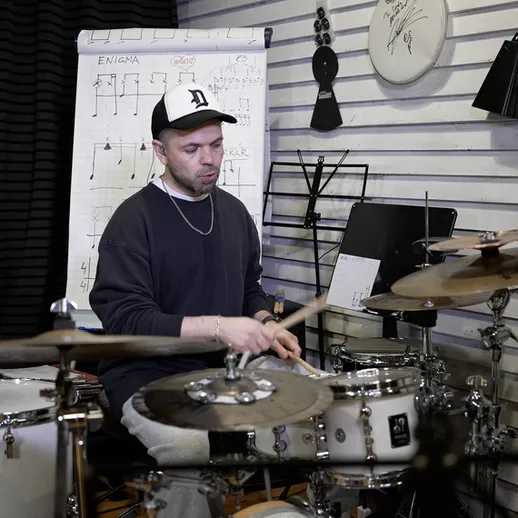 Музыкант играет на барабанах в студии звукозаписи во время репетиции