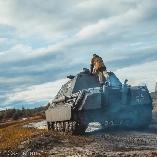 Солдаты на танке проезжают по лесной местности в солнечную погоду во время военных учений