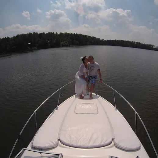 Пара на носу лодки наслаждаются днём на водоёме в солнечный летний день