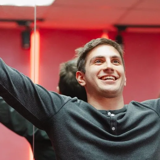 Парень с радостным выражением лица в помещении с ярким освещением