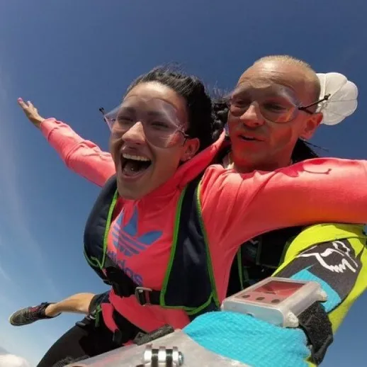 Экстремальный прыжок с парашютом над красивыми пейзажами, выполненный в ясный день с друзьями в открытом небе