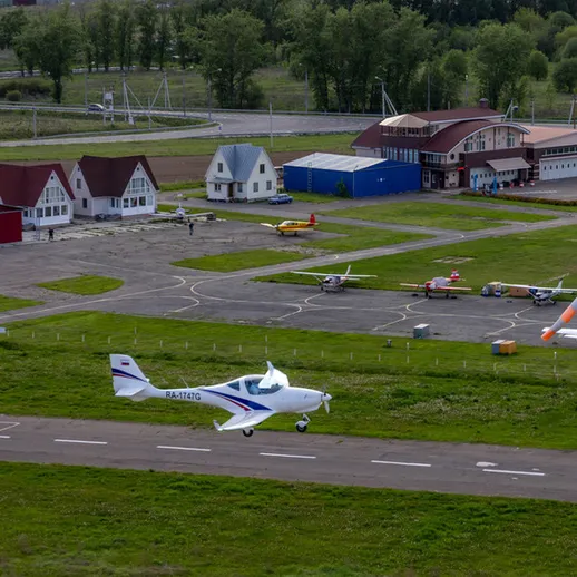 Летательный аппарат взлетает с аэродрома недалеко от живописного поселка в летний день