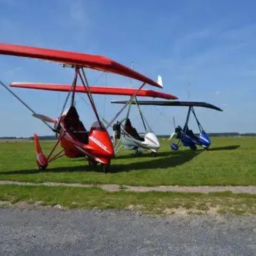 Три легких самолета различных цветов на травяном поле под ясным небом в солнечный день
