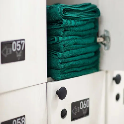 Полки с зелеными полотенцами в шкафчике для хранения в спортзале