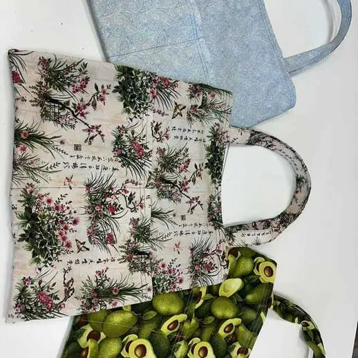 Стильные сумки из ткани на белом фоне в мастерской швейного ремесла