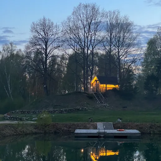 Небольшая дача на берегу озера в вечернее время с отражением в воде