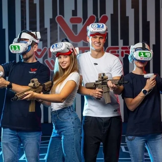 Участники играют в виртуальной реальности с контроллерами в игровом центре