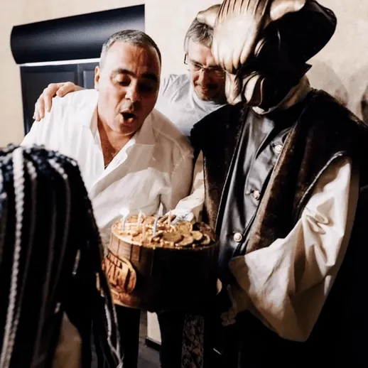 Мужчина задувает свечи на праздничном торте в компании друзей на вечеринке