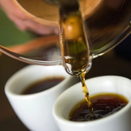 Чашки кофе наполняются свежезаваренным напитком на солнечной веранде