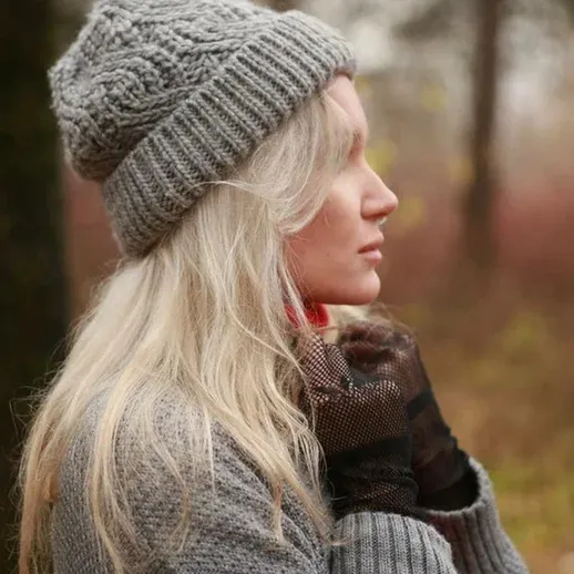 Молодая женщина в утепленном свитере и вязаной шапке наслаждается природой осеннего леса в прохладный день