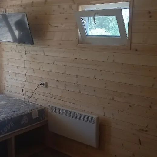 Уютная комната в деревянном доме с телевизором и большим окном для просмотра природы