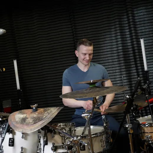 Музыкант играет на барабанах в звукозаписывающей студии в вечернее время