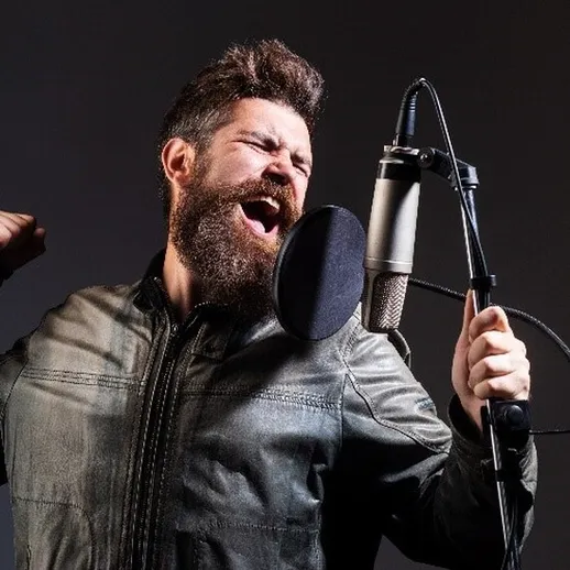 Музыкант поет в студии, наслаждаясь процессом записи в темном помещении