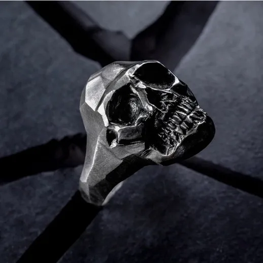 Мужской кольцо в виде черепа, сделанное из металла, на черном фоне с текстурой