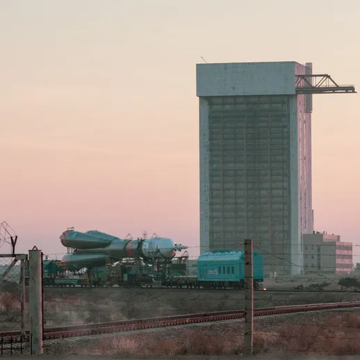 Заброшенные железнодорожные пути и высокое здание на фоне заката в промышленной зоне