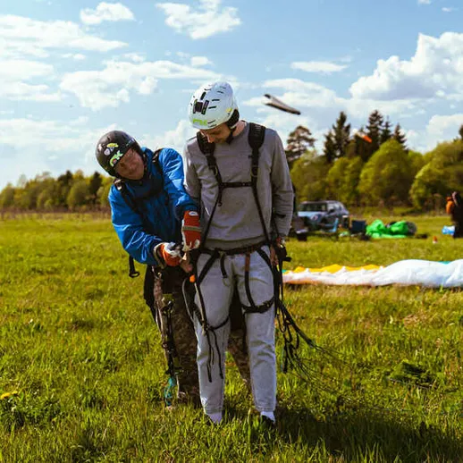 Подготовка к парапланеризму на зеленом поле в теплый день под ярким небом