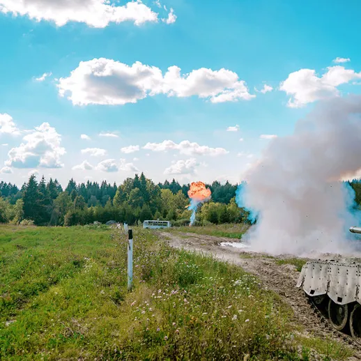 Танковая стрельба на полигоне в лесу в ясный день, дым и вспышка от выстрела