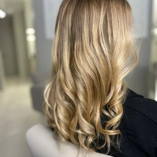 Прическа с локонами на длинных волосах в светлом салоне красоты
