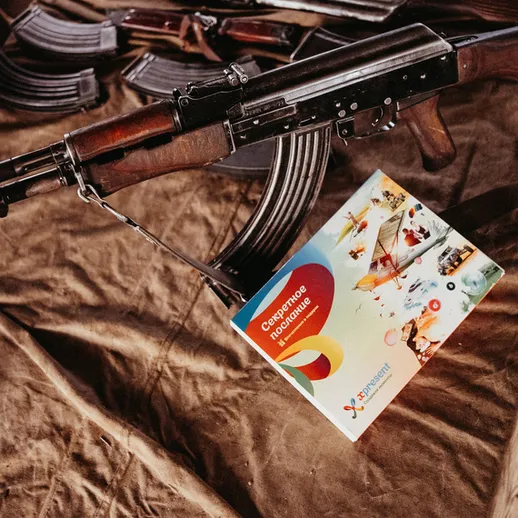 Автомат Калашникова с буклетом о военной выставке на столе в уютном помещении