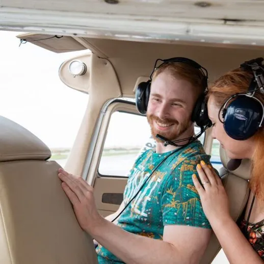 Пара наслаждается полетом на малом самолете, улыбается и общается