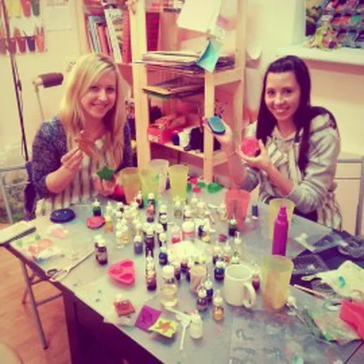 Две женщины занимаются рукоделием в творческой студии, наполняя стол красочными материалами и украшениями