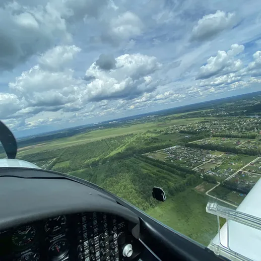 Полет на самолете над зелеными полями и деревнями в ясный день с облаками