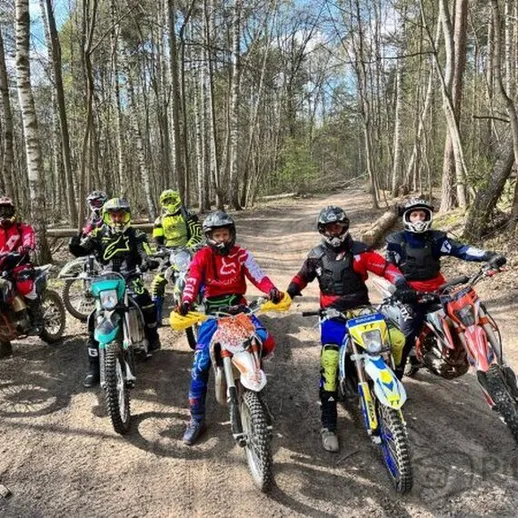 Группа мотоциклистов на травяной дорожке в лесу весной