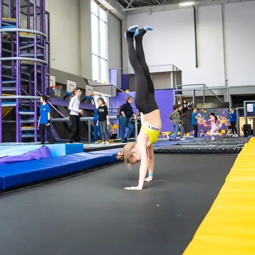 Девочка выполняет стенд на руках в тренажерном зале для акробатики в разгаре занятия