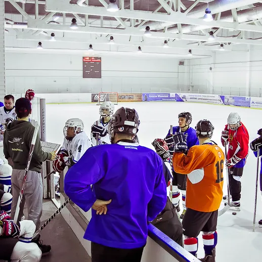 Хоккейная тренировка на льду в спортивном зале с игроками разных возрастов и уровней подготовки в зимний период