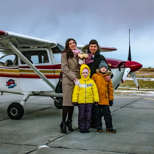 Семья на аэродроме рядом с небольшим самолетом, готовящееся к полету в зимний день под облачным небом