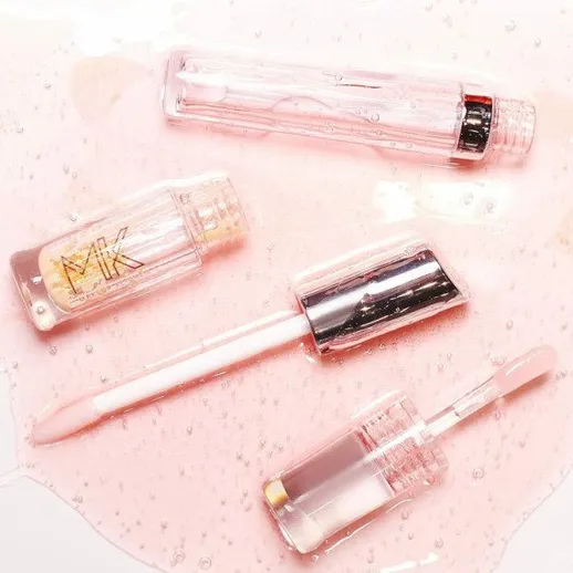 Косметические продукты на розовом фоне с каплями воды