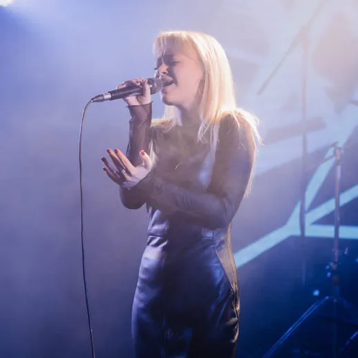 Концерт певицы в стильном черном наряде на сцене в клубе с ярким светом