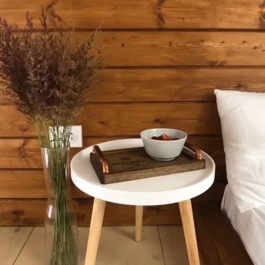 Уютный интерьер деревянного дома с столиком и цветами в вазе