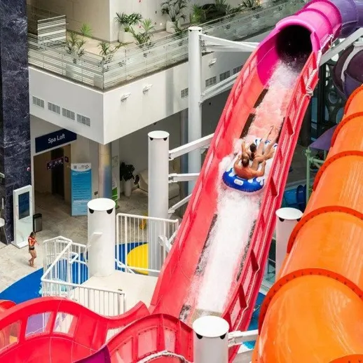 Два человека катятся вниз по водной горке в аквапарке в жаркий день