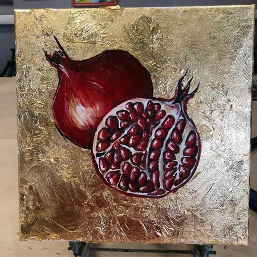 Мелкий натюрморт с гранатом и его разрезанной частью на золотом фоне в уютной мастерской художника