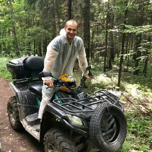 Мужчина на квадроцикле в лесу наслаждается поездкой по извивающейся дороге в летний день