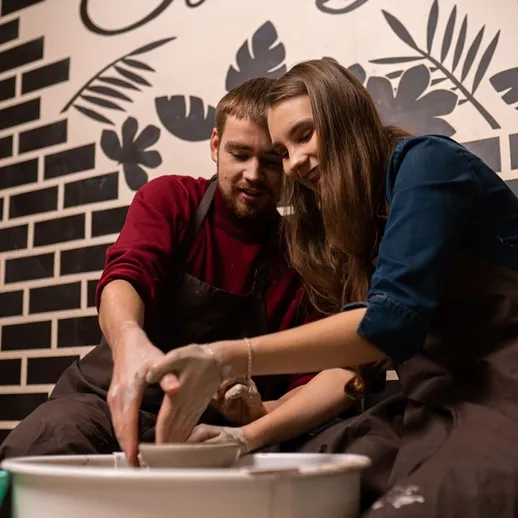 Урок гончарного мастерства в уютной студии с парами, работающими с глиной в теплой атмосфере