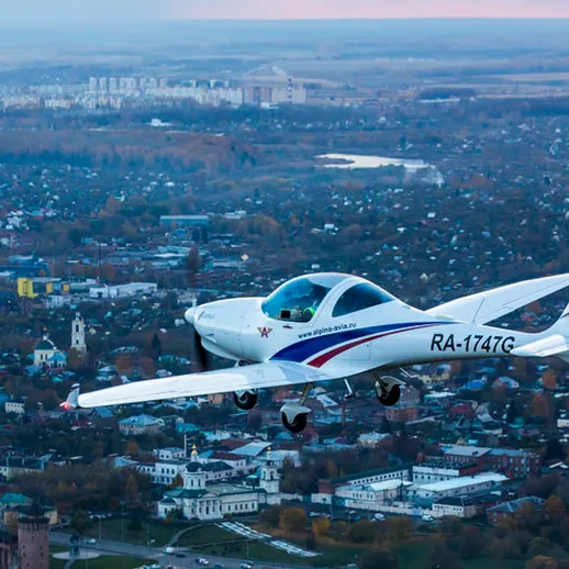 Небо над городом: малый самолет RA-1747G летит над историческим районом на закате