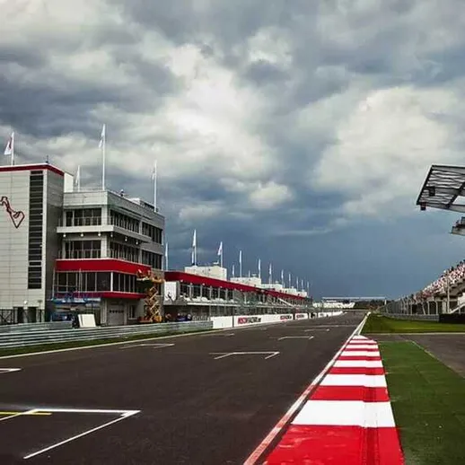 Автодром с трибунами и атмосферой напряжённой гонки под грозовыми облаками