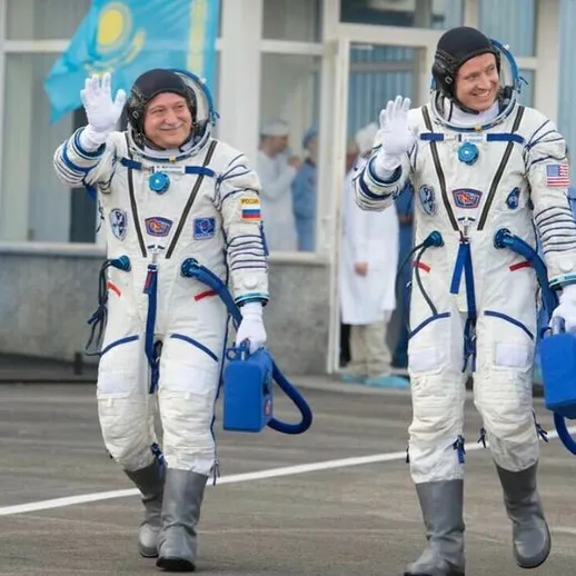 Космонавты приветствуют зрителей перед стартом ракеты с космодрома Баikonur в Казахстане