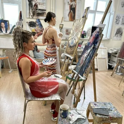 Женщины, занятые рисованием в художественной студии, создают картины на мольбертах в дневное время