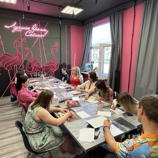 Группа людей рисует в художественной студии с яркими стенами и неоновыми элементами интерьера