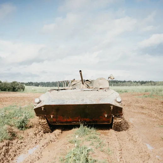 Военная техника на грязной дороге в лесистой местности под облачным небом в летний день