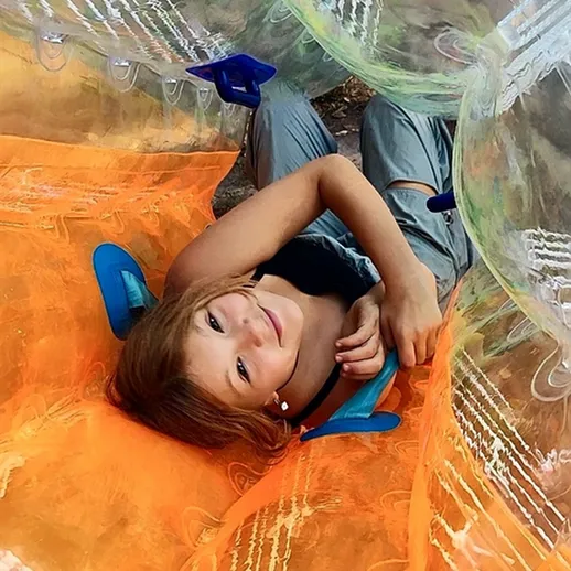 Ребёнок на водной аттракционе в прозрачном шаре на открытом воздухе в летний день