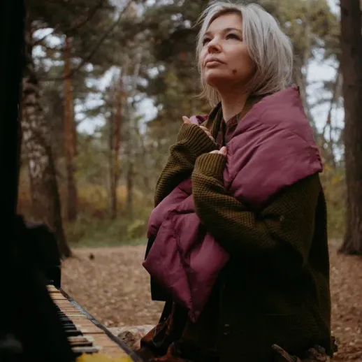 Музыкантка на рояле в лесу наслаждается осенним днем с теплым пледом