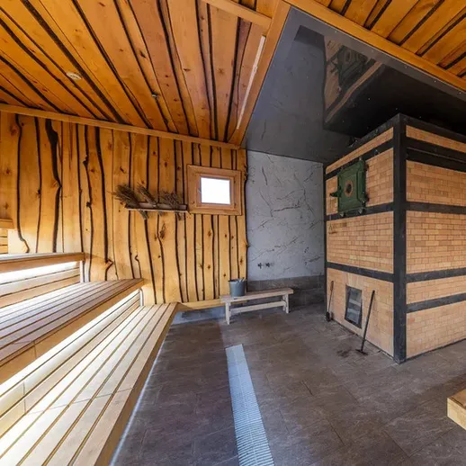 Внутри сауны с деревянными стенами и печью, расположенной в загородном доме