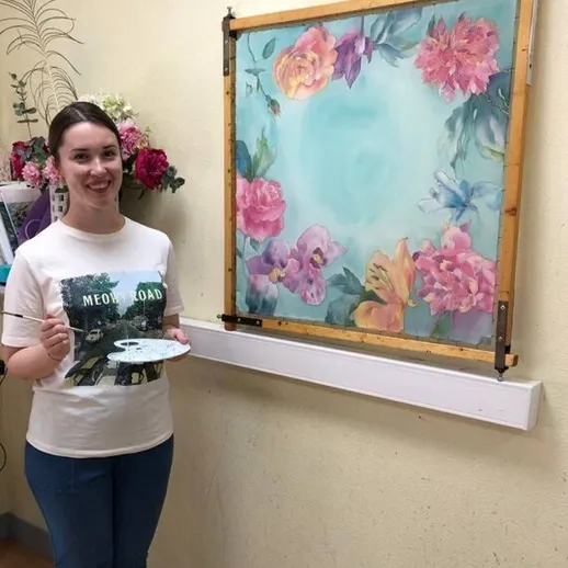 Молодая женщина рисует картину с цветами в художественной студии во время занятия