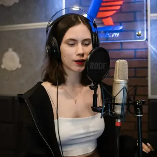 Молодая певица записывает песню в студии звукозаписи