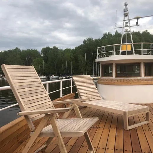 Уютные деревянные шезлонги на палубе лодки у берега реки в ясный день