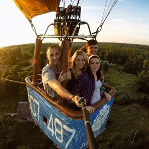Четыре человека наслаждаются полетом на воздушном шаре на закате в живописном месте
